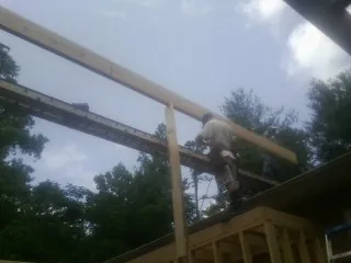 Carpenter setting a ridge beam over a new addition frame — Ice Dam Removal by Roofing Brothers in Croswell