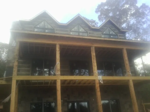 Dormers and porch framing on a large log home under construction — Roof Coating work by our crew in Croswell