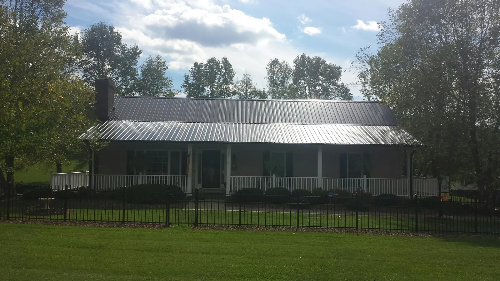 Gray metal roof on a brick ranch with a full width front porch — Gutter Guard Installation work by our crew in Croswell