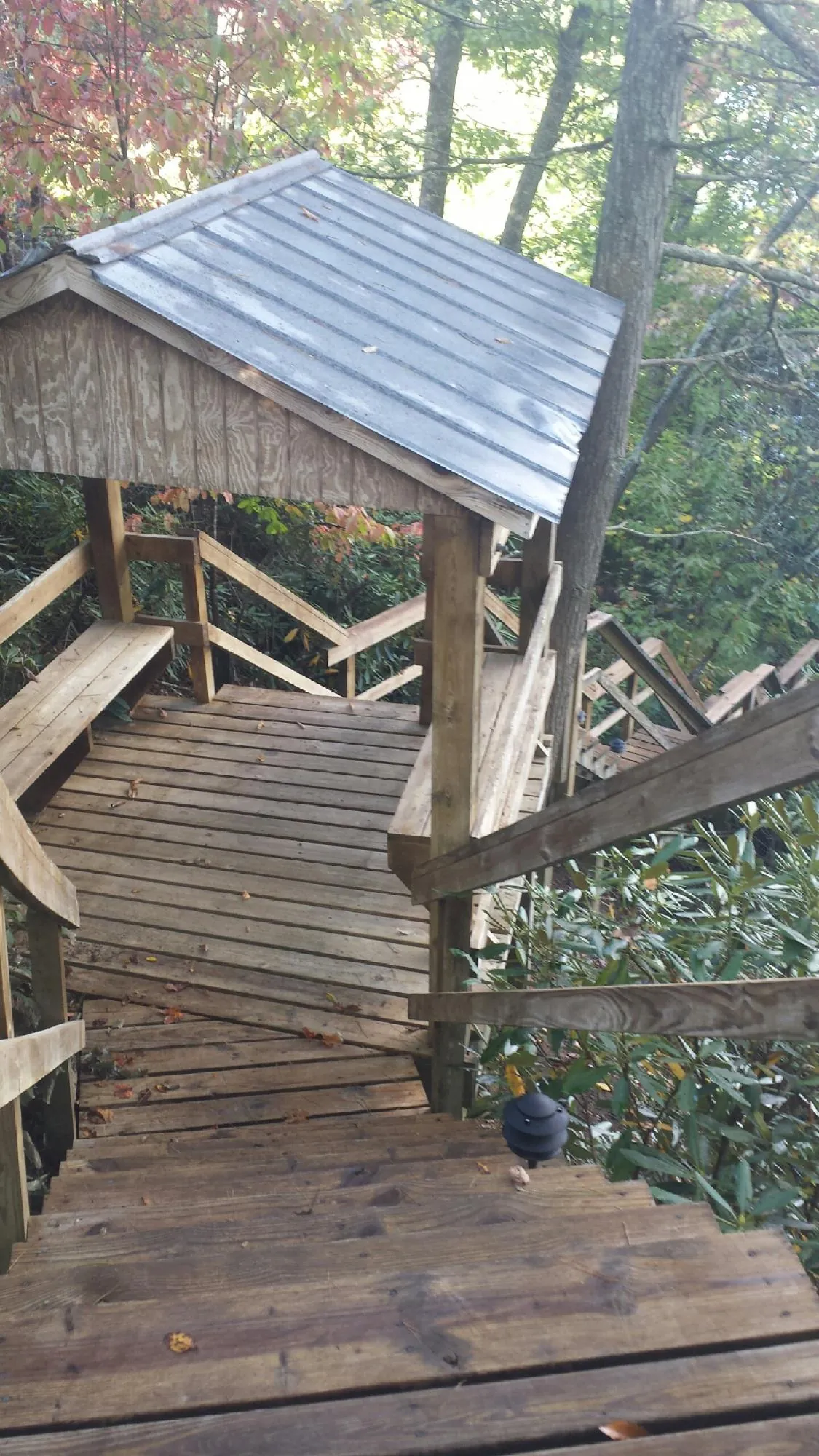 Metal roofed shelter over wooden steps on a wooded walkway — Skylight Repair & Installation work by our crew in Croswell